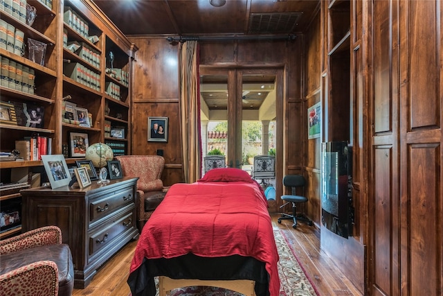 bedroom with wooden ceiling, light wood-type flooring, and wood walls