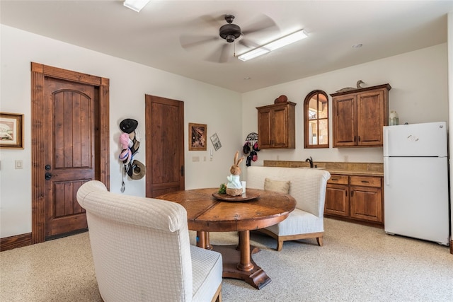 dining area with light colored carpet, sink, and ceiling fan