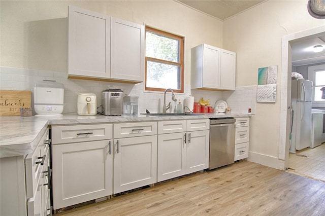 kitchen with light wood-style floors, plenty of natural light, white cabinets, and dishwasher