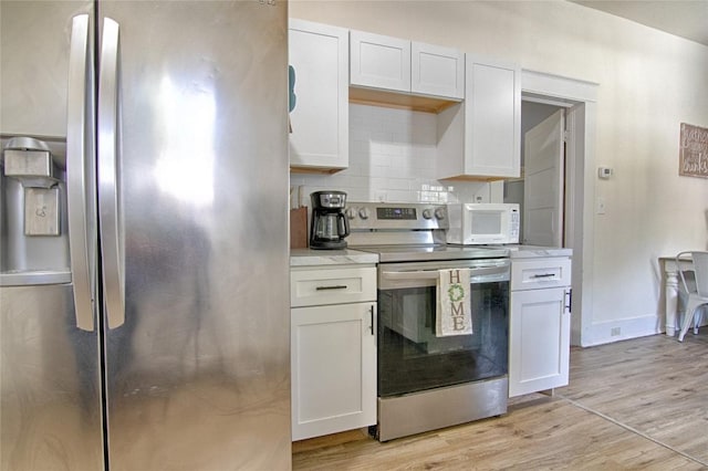 kitchen featuring white cabinetry, baseboards, appliances with stainless steel finishes, light wood-type flooring, and decorative backsplash