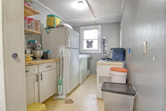 kitchen with freestanding refrigerator, open shelves, white cabinetry, and washer and dryer