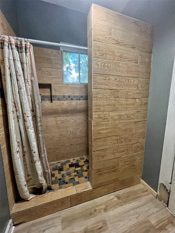 full bathroom featuring a tile shower and wood finished floors