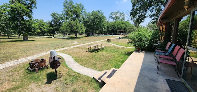 view of community with a patio, a fire pit, and a lawn