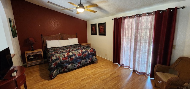 bedroom with ceiling fan, light hardwood / wood-style flooring, vaulted ceiling, and a textured ceiling