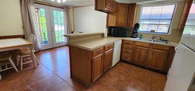 kitchen featuring white appliances, kitchen peninsula, and tile patterned flooring