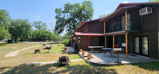 view of yard featuring a wall mounted AC, a patio area, a balcony, and a fire pit