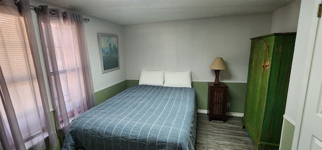 bedroom featuring dark wood-type flooring, multiple windows, and a textured ceiling