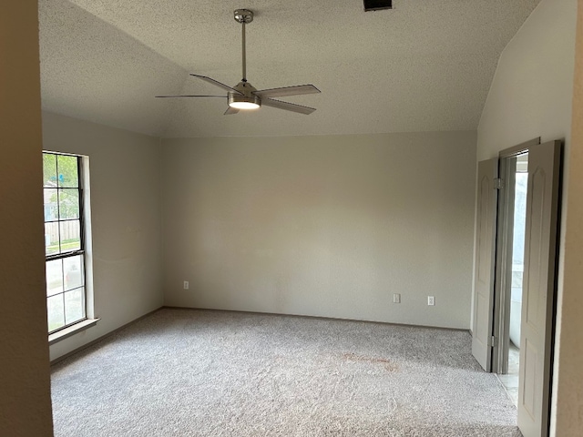 empty room with ceiling fan, light colored carpet, a textured ceiling, and lofted ceiling