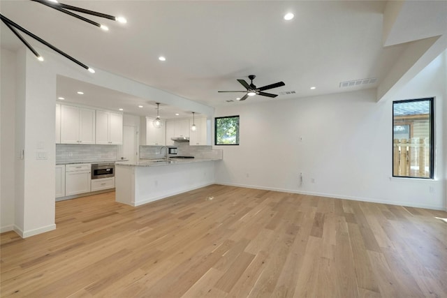 unfurnished living room with light hardwood / wood-style flooring, sink, and ceiling fan