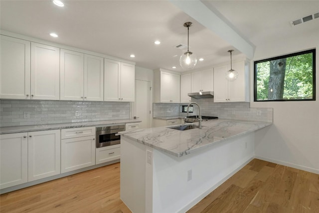 kitchen featuring decorative backsplash, kitchen peninsula, white cabinets, wall oven, and light hardwood / wood-style floors