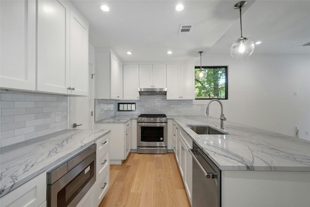 kitchen featuring light hardwood / wood-style flooring, appliances with stainless steel finishes, pendant lighting, tasteful backsplash, and sink