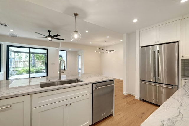 kitchen featuring stainless steel appliances, light wood-type flooring, ceiling fan, sink, and decorative light fixtures