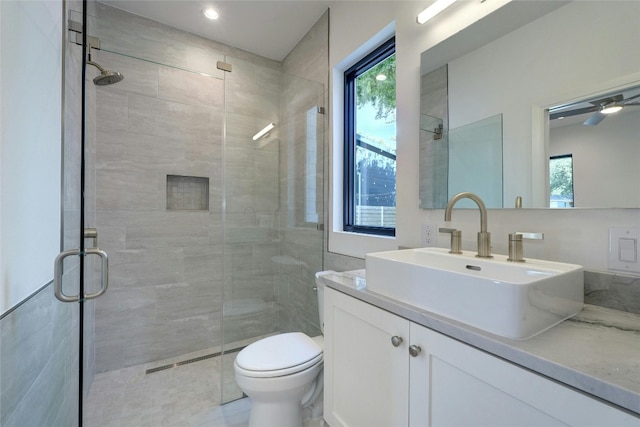 bathroom featuring toilet, vanity, ceiling fan, and an enclosed shower