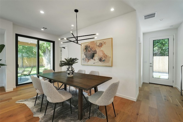 dining space featuring light hardwood / wood-style flooring, a notable chandelier, and a healthy amount of sunlight