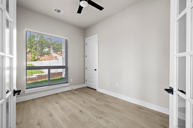 empty room with french doors, ceiling fan, and light hardwood / wood-style flooring