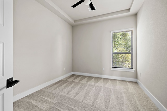 carpeted empty room with a raised ceiling and ceiling fan