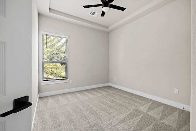 unfurnished room with light carpet, ceiling fan, and a tray ceiling