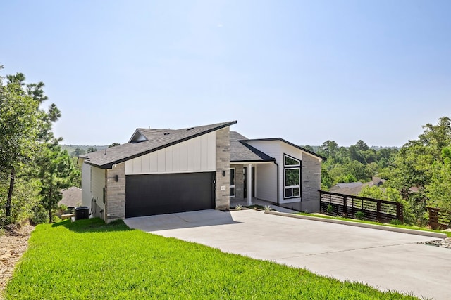 view of front of home featuring a garage, central AC, and a front lawn