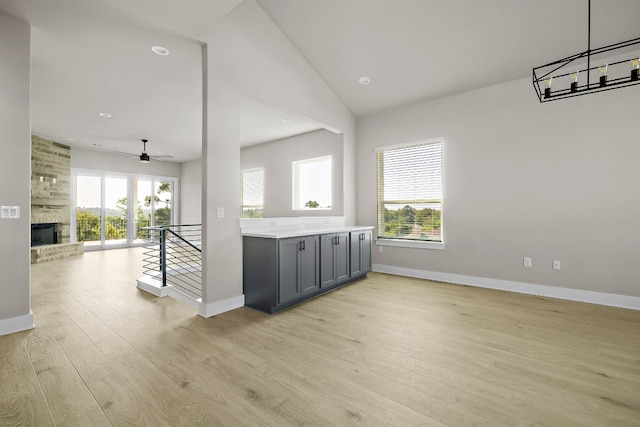 kitchen with plenty of natural light, gray cabinetry, light hardwood / wood-style floors, and a brick fireplace