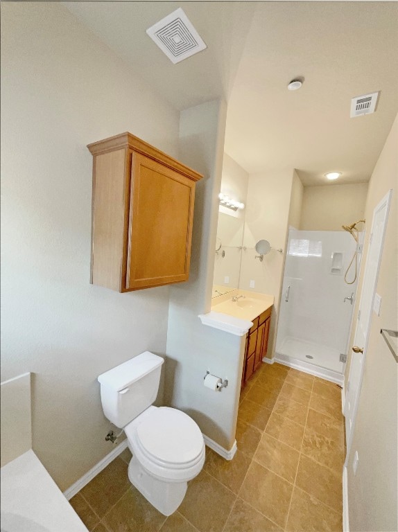 bathroom featuring a tile shower, vanity, tile patterned flooring, and toilet