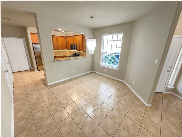 kitchen with light tile patterned floors, stainless steel appliances, hanging light fixtures, and kitchen peninsula