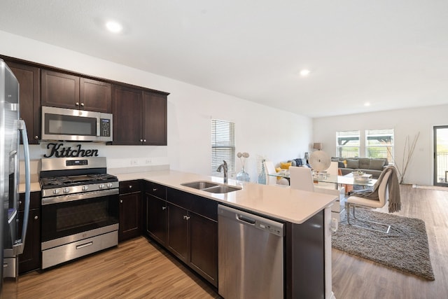 kitchen featuring appliances with stainless steel finishes, sink, kitchen peninsula, and light hardwood / wood-style floors