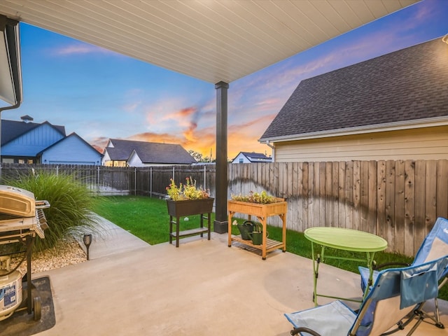 patio terrace at dusk featuring a lawn