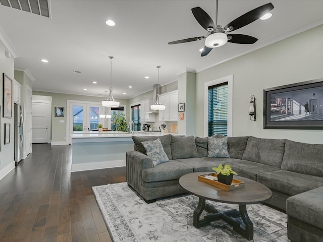 living room featuring ceiling fan, crown molding, a wealth of natural light, and dark wood-type flooring