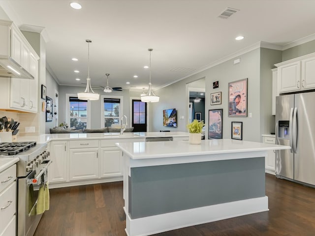 kitchen with kitchen peninsula, appliances with stainless steel finishes, ceiling fan, sink, and a center island