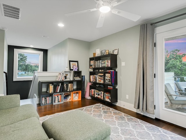 living area featuring ceiling fan and dark wood-type flooring