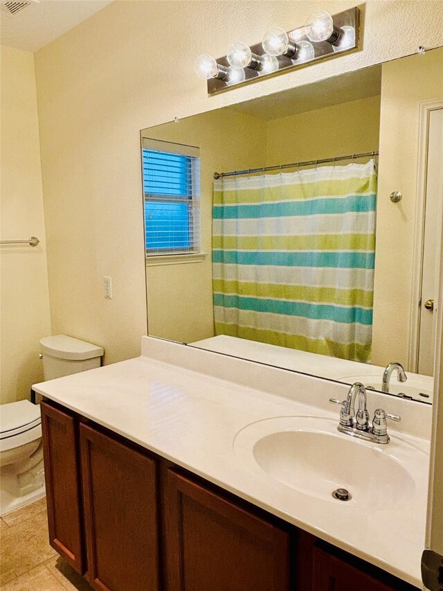 bathroom with tile patterned flooring, vanity, and toilet