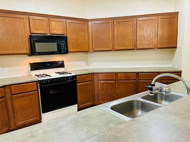 kitchen featuring gas range oven, backsplash, and sink