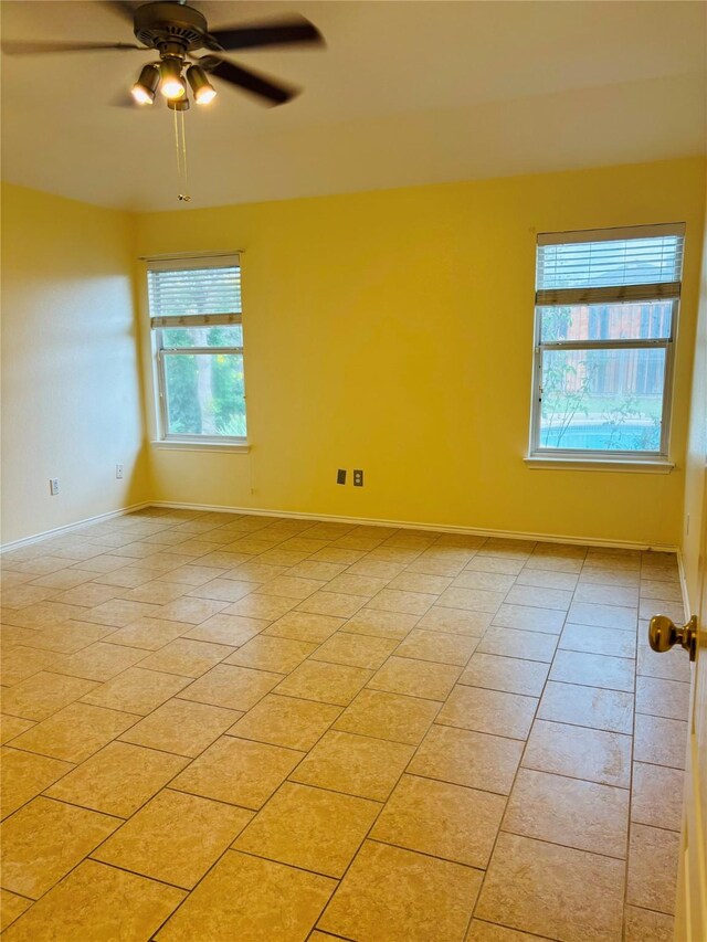 spare room featuring light tile patterned floors, a wealth of natural light, and ceiling fan