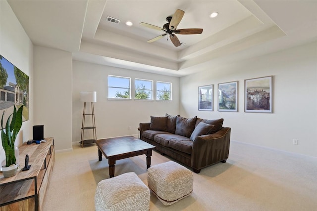 carpeted living room featuring a raised ceiling and ceiling fan