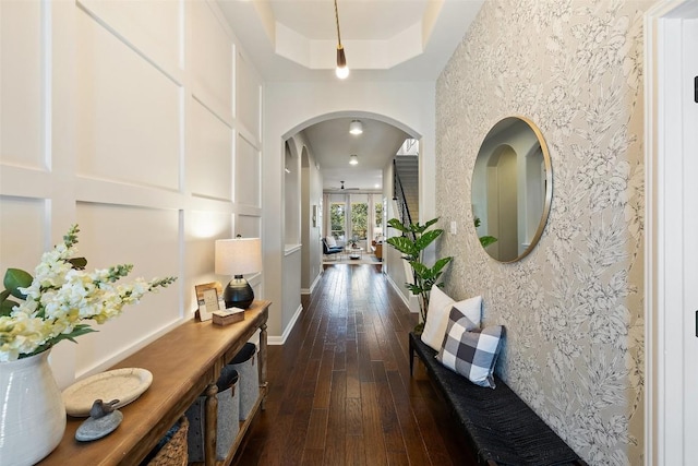 hall with dark wood-type flooring and a tray ceiling