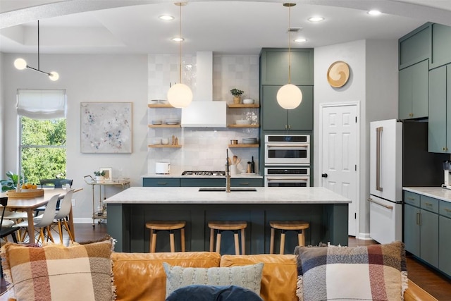 kitchen with dark wood-type flooring, a breakfast bar, stainless steel gas cooktop, a center island with sink, and decorative backsplash