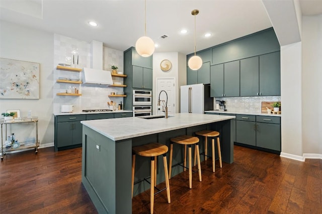 kitchen with appliances with stainless steel finishes, a breakfast bar, sink, dark wood-type flooring, and a center island with sink