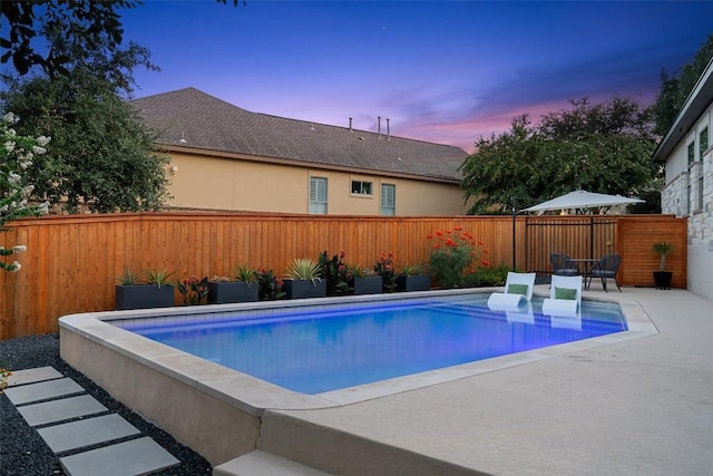 pool at dusk with a patio area