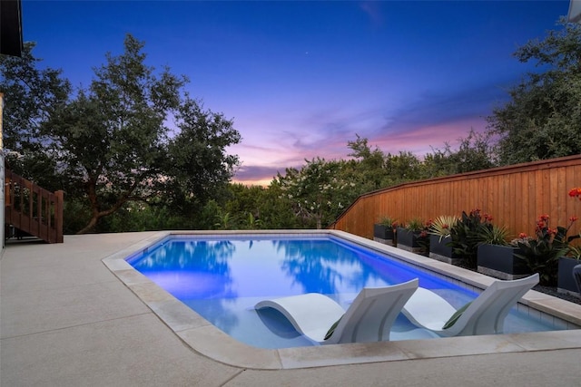 pool at dusk with a patio area