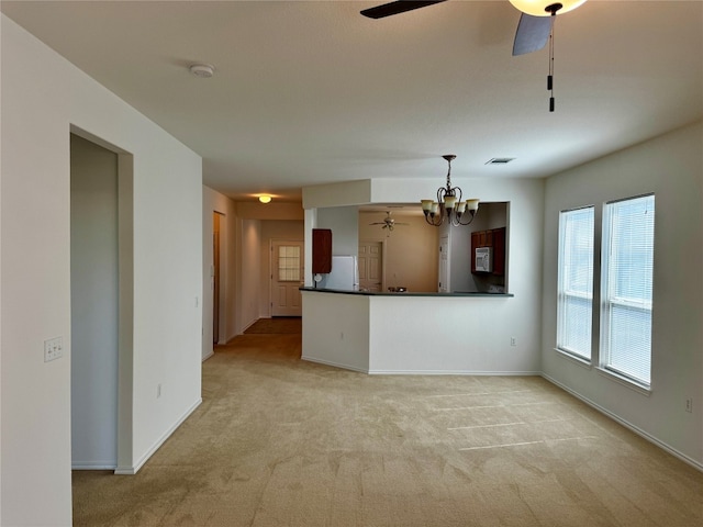 unfurnished living room with ceiling fan with notable chandelier and light carpet