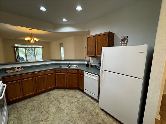 kitchen featuring pendant lighting, white appliances, kitchen peninsula, and a notable chandelier