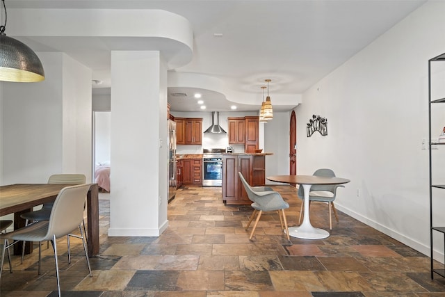 kitchen featuring appliances with stainless steel finishes, pendant lighting, and wall chimney range hood