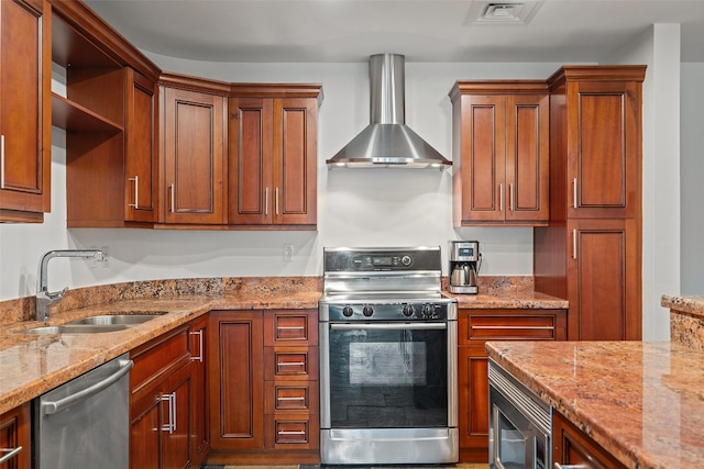 kitchen with light stone counters, stainless steel appliances, wall chimney exhaust hood, and sink