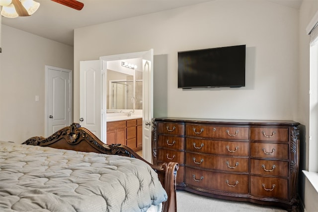 bedroom with ceiling fan, sink, light carpet, and ensuite bath