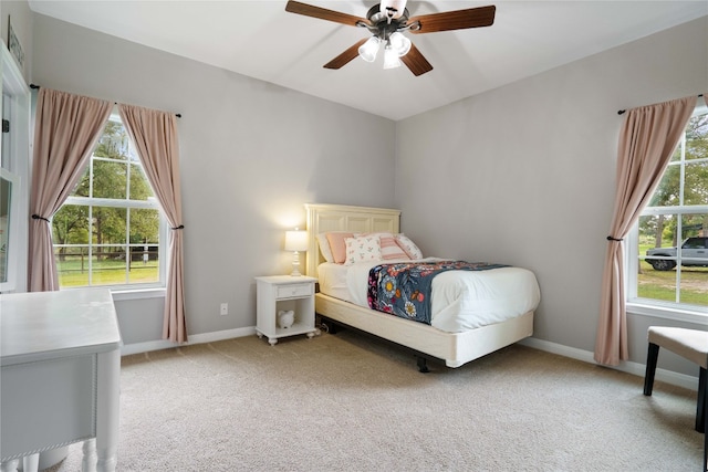 bedroom featuring ceiling fan, light carpet, and multiple windows