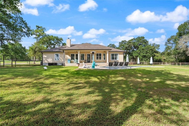 back of property featuring a patio, a swimming pool, and a lawn