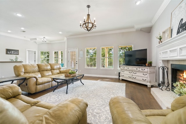 living room with a notable chandelier, a tiled fireplace, dark wood-type flooring, and ornamental molding