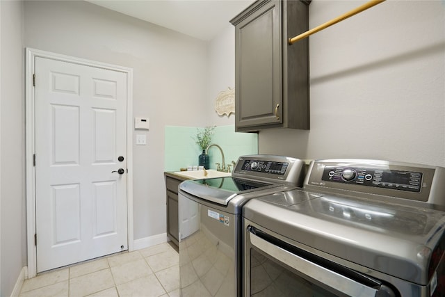 laundry room with light tile patterned floors, sink, cabinets, and washer and clothes dryer