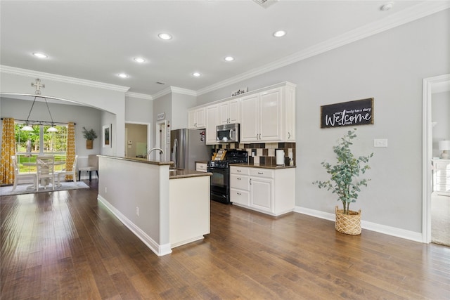 kitchen featuring decorative backsplash, crown molding, stainless steel appliances, white cabinets, and dark hardwood / wood-style floors