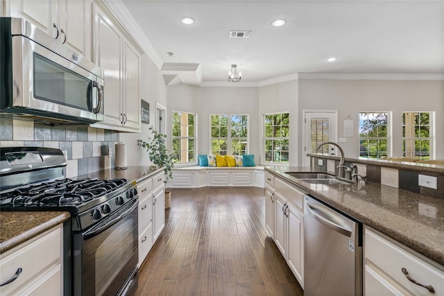 kitchen featuring crown molding, dark hardwood / wood-style floors, appliances with stainless steel finishes, sink, and tasteful backsplash